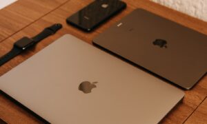 silver macbook beside black iphone 7 on brown wooden table