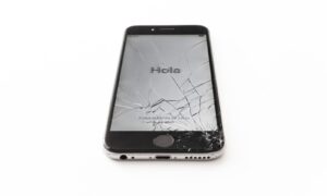 an iphone with a cracked screen on a white surface